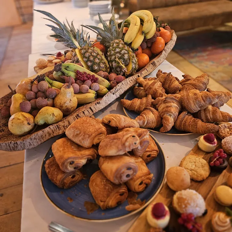 Table de brunch : viennoiseries, fruits frais et petites pâtisseries.