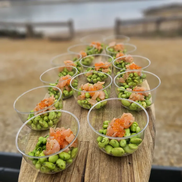 Verrines d'edamame et saumon fumé alignées sur une planche.