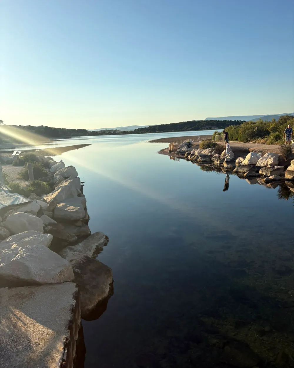 La lagune au petit matin, entre les rochers blancs du rivage.