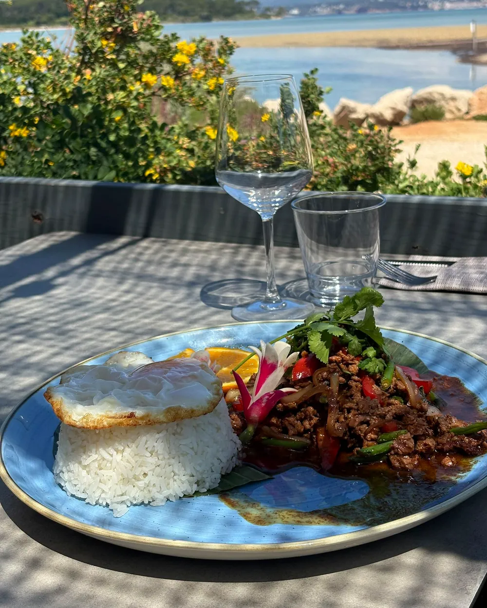 Un plat thaï — riz, bœuf sauté au basilic et légumes — servi en terrasse face à la lagune.